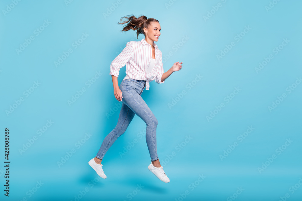 Full length body size profile side view of lovely sporty cheerful girl jumping running action isolated on bright blue color background