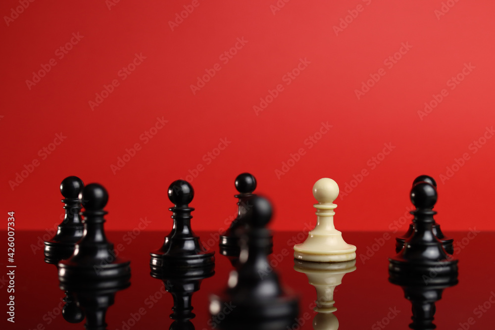 The concept of leadership, the white pawn piece stands out from the crowd of black The concept of leadership, the white pawn piece stands out from the crowd of black