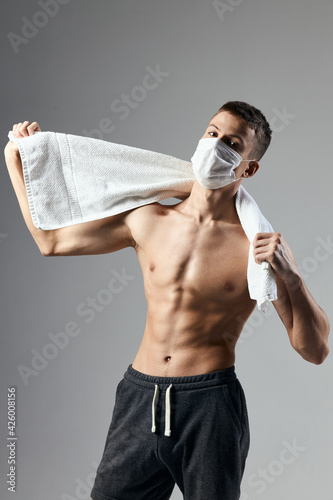 sporty man in medical mask holding towels behind his head workout lifestyle