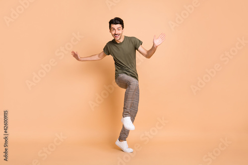Full length body size photo of dancing guy enjoying party in checkered pants smiling isolated on pastel beige color background