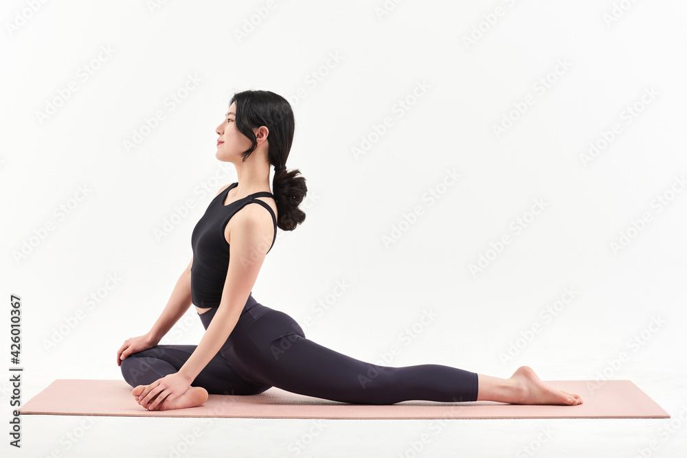 Fototapeta premium 하얀 배경에서 요가 자세를 하고 있는 20대 한국 여자 모델. 유연한 몸, 아름다운 몸, 귀여운 얼굴