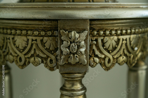 Antique round metal bronze table detail decorated with abstract patterns, close-up view. Piece of furniture with floral ornate. Concept of furniture design. Can be used as dressing or coffee table 