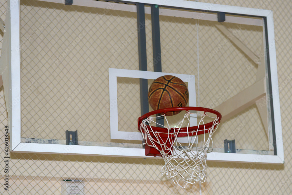 a worn basketball flies into the basket