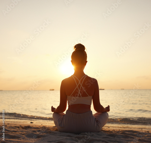 Calm woman meditating on beach at sunset