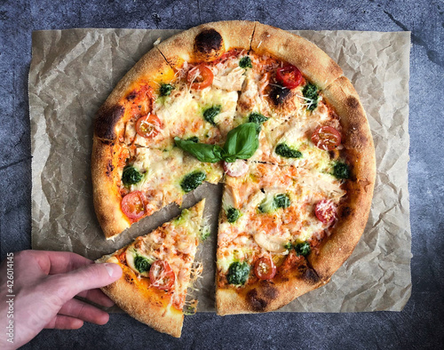 Pizza on a black background with tomatoes, pesto and cheese flat lay