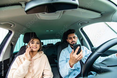 road trip, travel, destination technology and people concept. Happy indian man and woman with navigator on smartphone driving in car