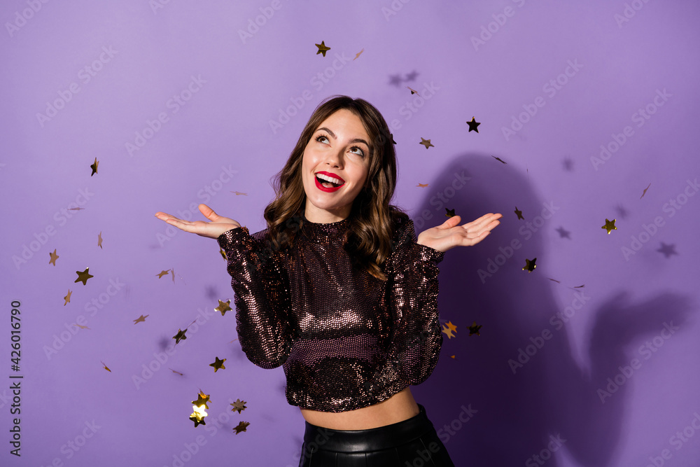 Portrait of charming cheerful girl having fun sequins flying festal day isolated over bright violet color background