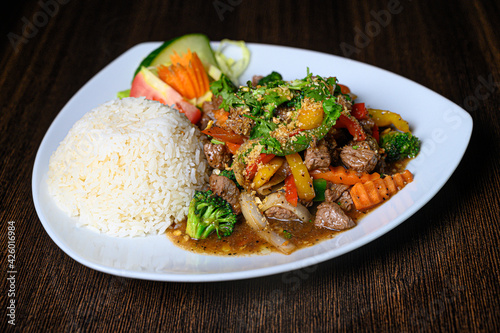 Thai food with beef, vegetables and rice on a white plate