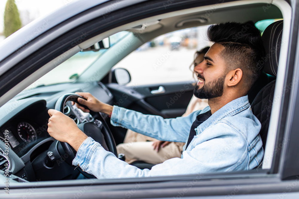 Enjoying travel. Beautiful young indian couple sitting on the front passenger seats and smiling while handsome man driving a car Enjoying travel. Beautiful young indian couple sitting on the front passenger seats and smiling while handsome man driving a car