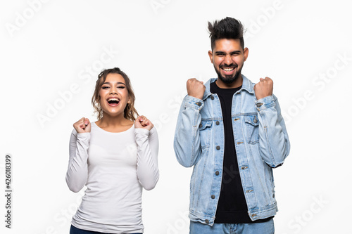 Happy indian couple with arms up celebrating isolated over white background