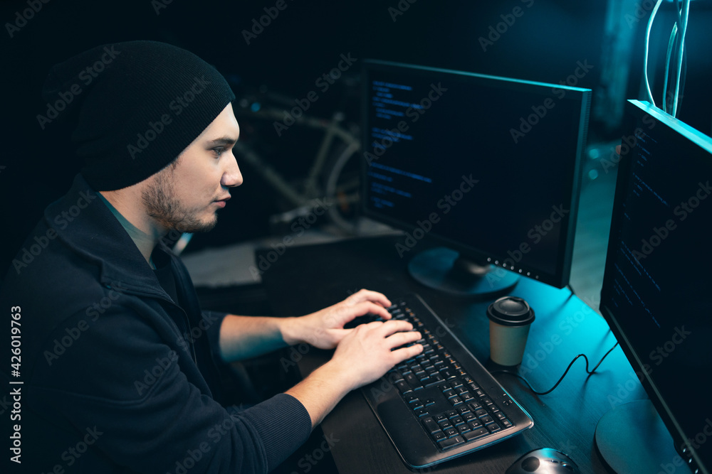 Concentrated hacker in sweatshirt and cap Breaks into corporate servers from his underground hideout. The anonymous programmer you are looking for analyzes the next move of the cyber attack. Concentrated hacker in sweatshirt and cap Breaks into corporate servers from his underground hideout. The anonymous programmer you are looking for analyzes the next move of the cyber attack.