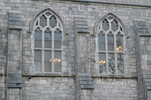 Old gothic arched carved leaded window in an old church with flint walls