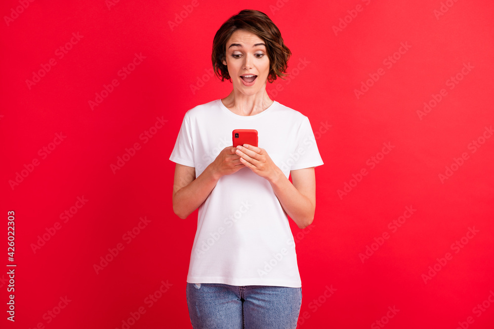 Portrait of attractive cheerful focused girl using device gadget browsing web isolated over bright red color background Portrait of attractive cheerful focused girl using device gadget browsing web isolated over bright red color background