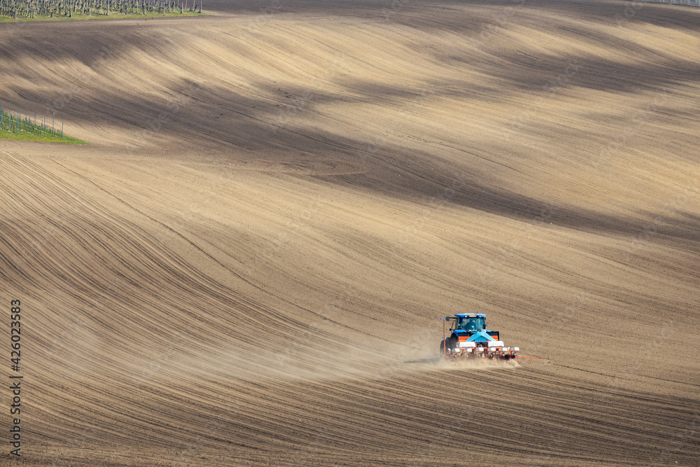 Tractor with seed drill in early spring landscape