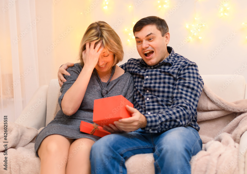 portrait of adult romantic couple sitting on a couch at home, holiday lights on a wall portrait of adult romantic couple sitting on a couch at home, holiday lights on a wall