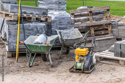Road and pavement constuction work site with bricks piles, rammer machine and carts. Stock photo