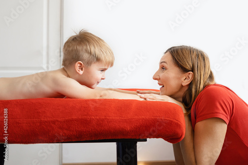 Mom and 5 year old son relax and play together in bed on weekends, lazy morning, warm and cozy scene. red and white colors