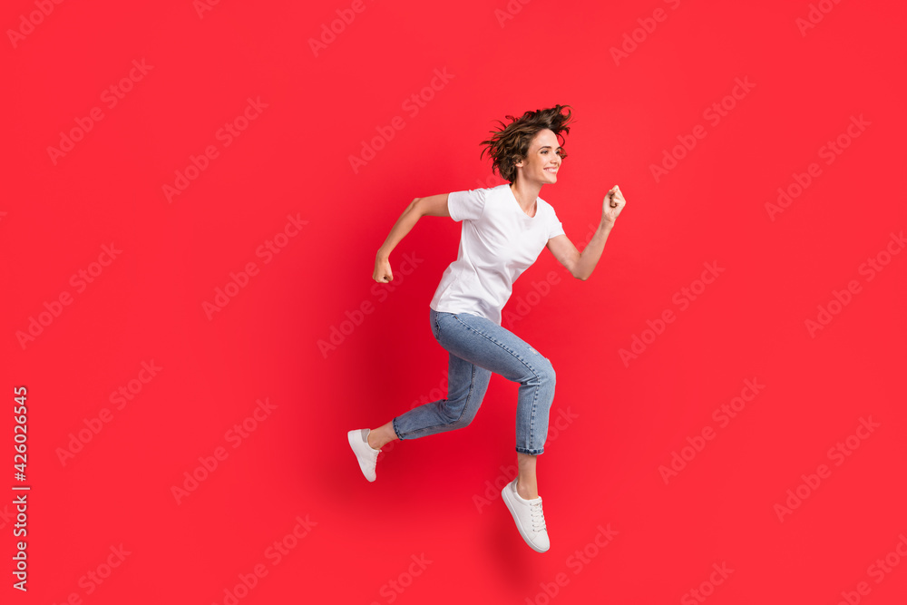 Full length body size view of attractive motivated cheerful girl jumping running fast isolated over bright red color background Full length body size view of attractive motivated cheerful girl jumping running fast isolated over bright red color background
