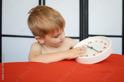 serious little boy holding a watch and examining the dial