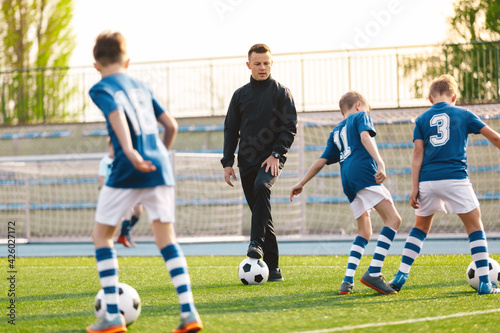 School Sports Teacher on Training with Children Team. Young Man Coaching Kids at Football Class