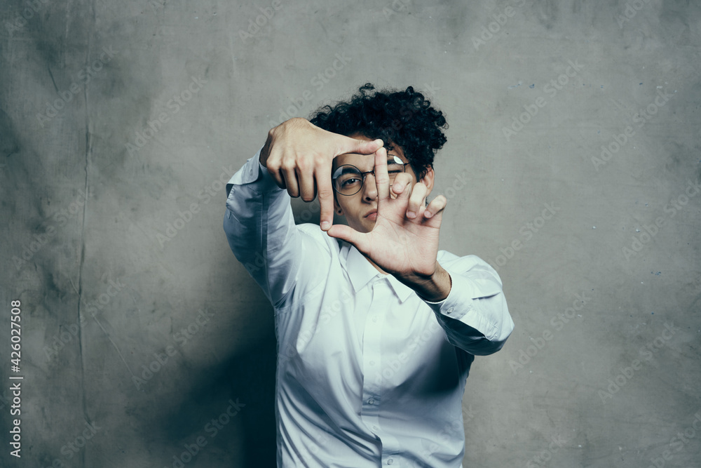 fashionable guy with curly hair gesturing with his hands on a gray background portrait close-up fashionable guy with curly hair gesturing with his hands on a gray background portrait close-up