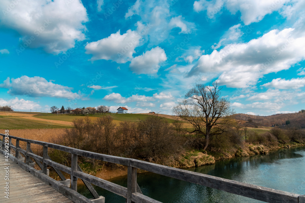 Rural landscape, wooden bridge and blue sky with clouds