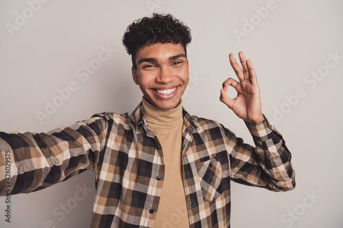 Photo of trendy handsome brunette dark skin man make selfie show okay sign isolated on grey color background