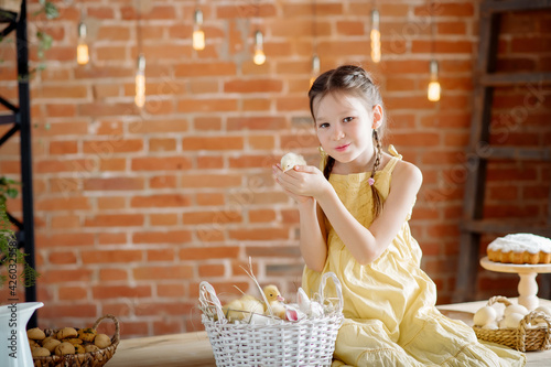 A cute little girl plays with her pets: ducklings and chickens on the festive table, getting ready for the Easter holiday
