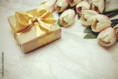 Gift boxes with gold ribbon and tulip flower bouquet on marble background