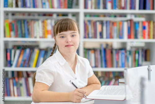 Smiling girl with syndrome down at library. Education for disabled children concept
