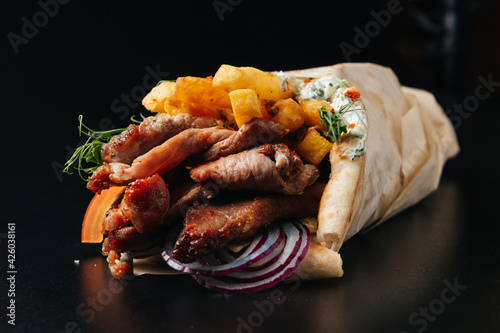 Greek gyros wrapped in pita breads on black background. Gyro pita, shawarma, take away, street food