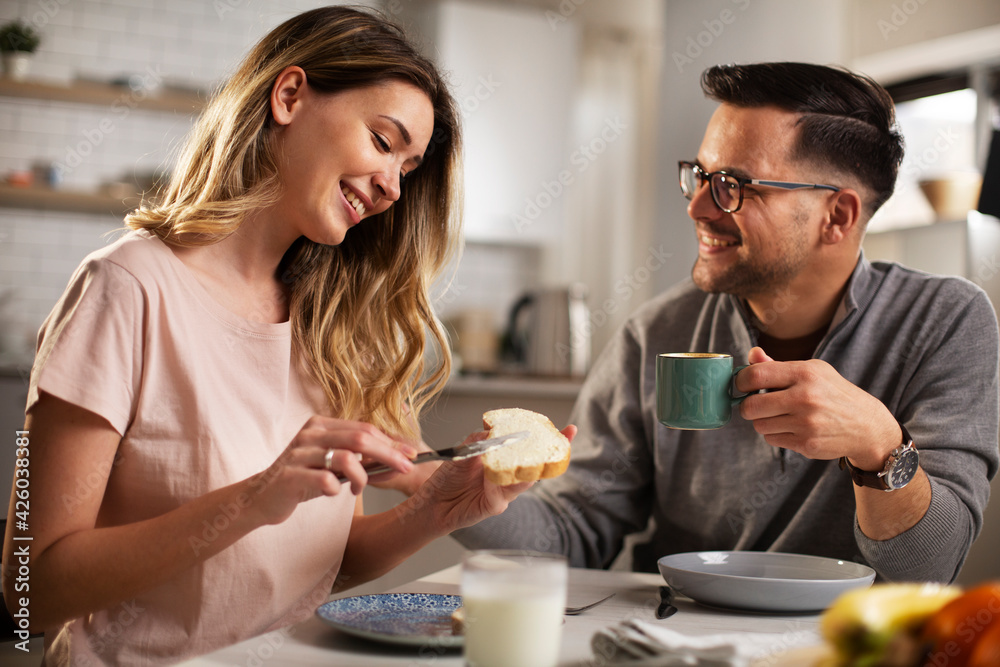 Beautiful woman enjoying in breakfast with her boyfriend. Happy young couple drinking coffee and eating sandwich at home.. Beautiful woman enjoying in breakfast with her boyfriend. Happy young couple drinking coffee and eating sandwich at home..