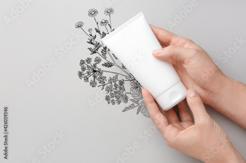 Female hands with cream on grey background