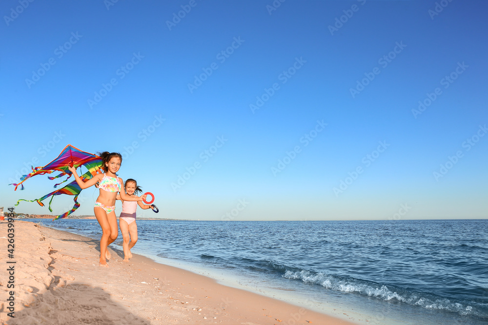 Cute little girls flying rainbow kite on sea beach Cute little girls flying rainbow kite on sea beach