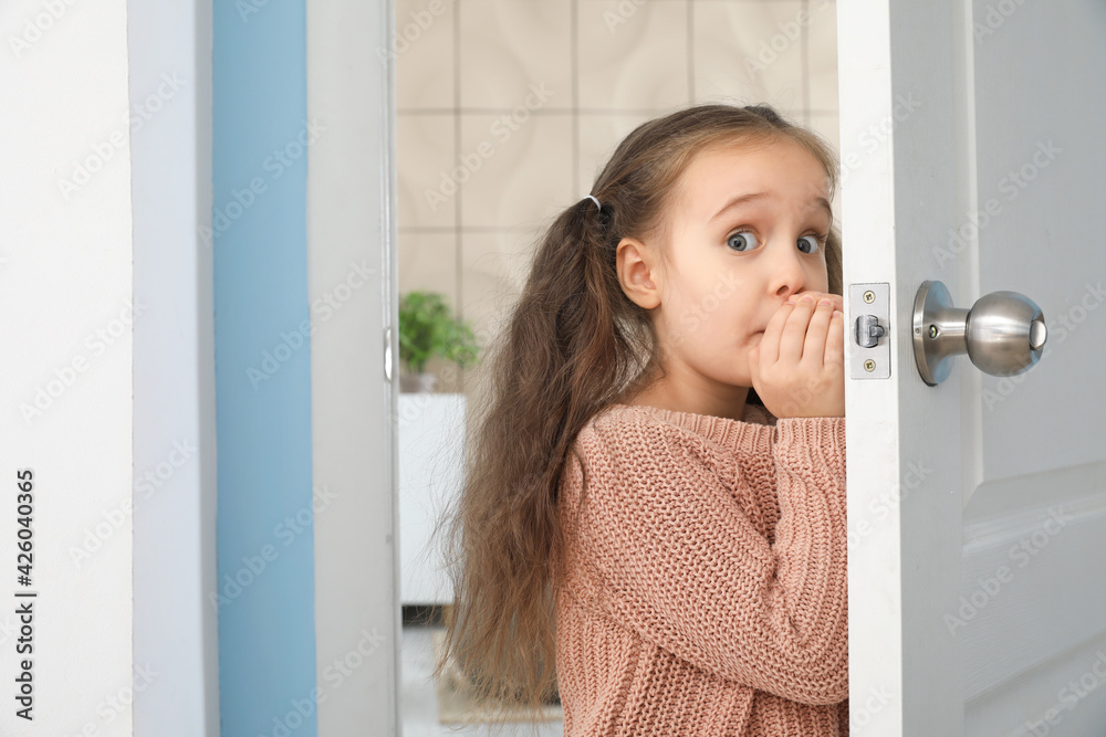 Scared little girl standing in doorway