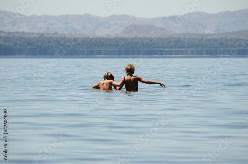 children hugging in the water, lake and mountains
