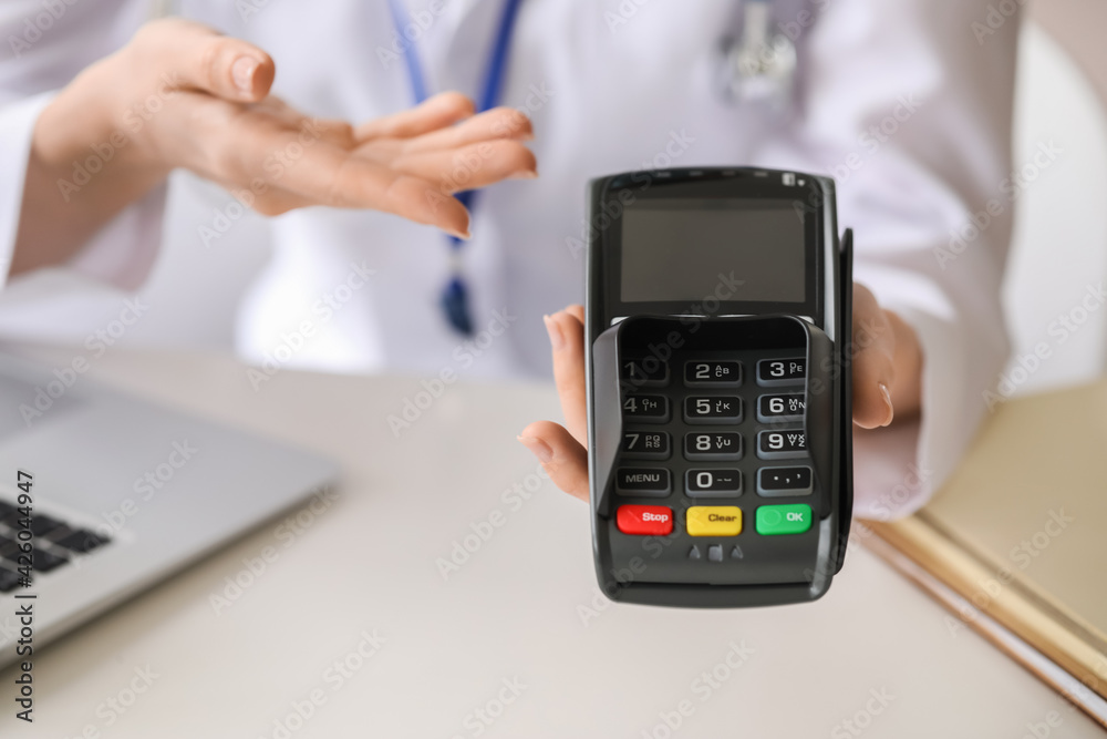 Doctor with payment terminal in clinic, closeup Doctor with payment terminal in clinic, closeup