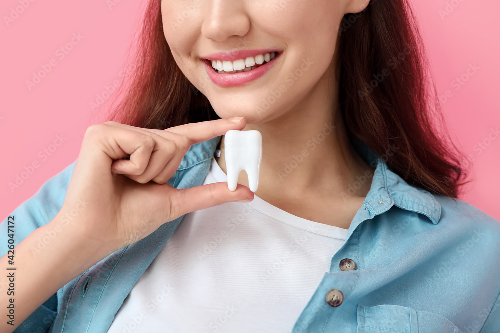 Beautiful young woman with plastic tooth on color background, closeup Beautiful young woman with plastic tooth on color background, closeup