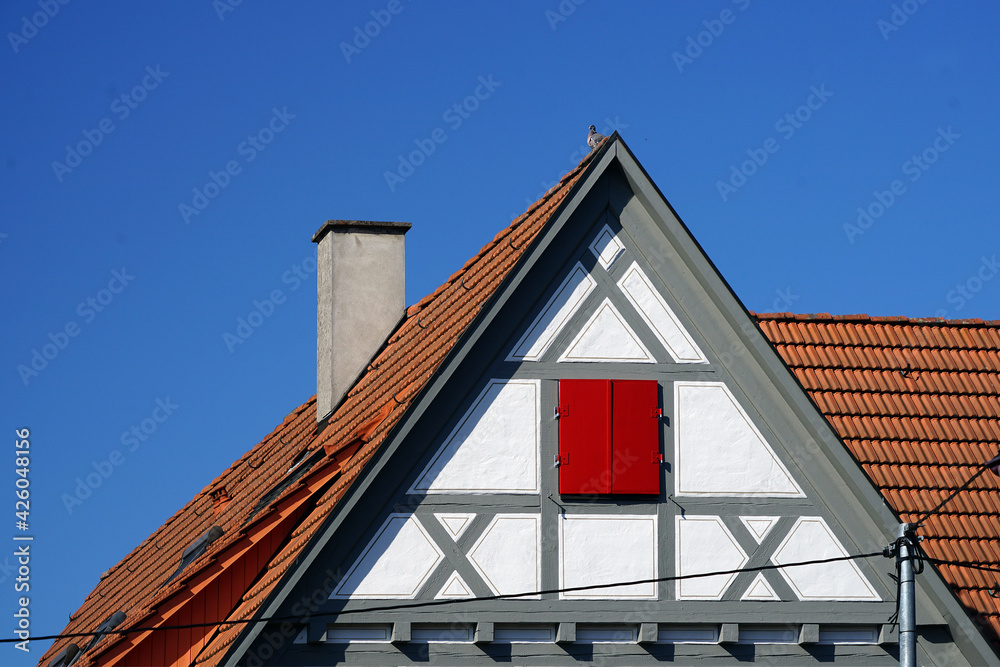 Weisses Fachwerkhaus mit rotem Fensterladen im Dachgiebel