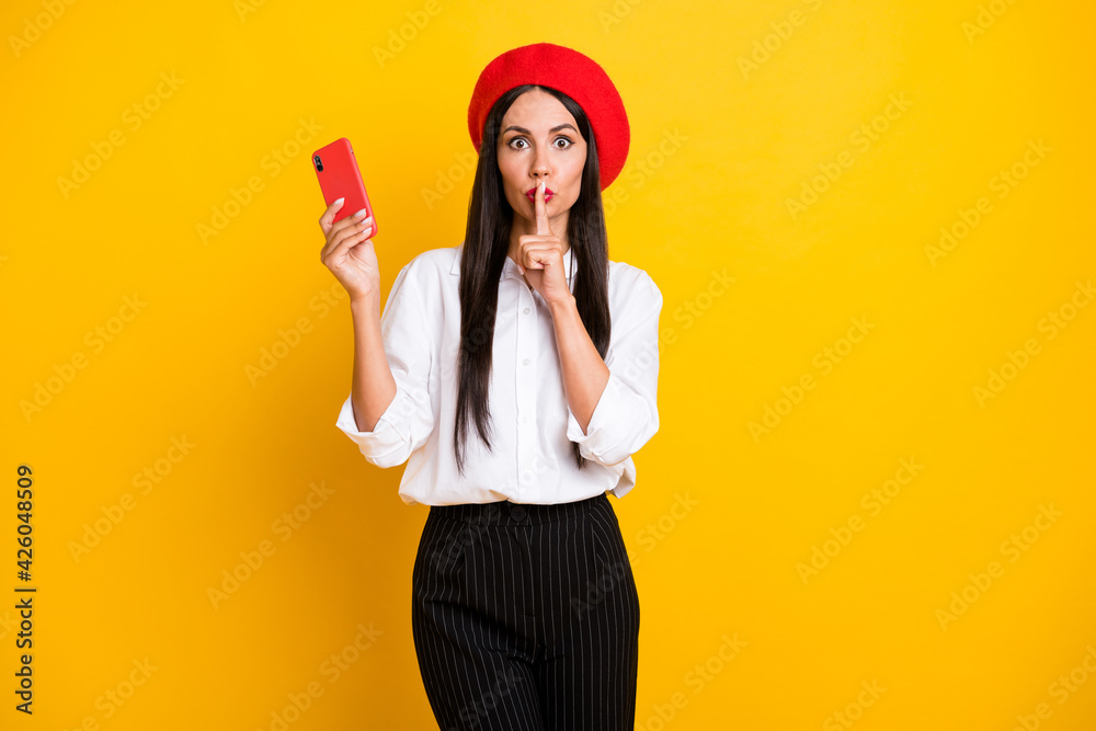Photo of beautiful stunning gorgeous french woman hold cellphone cover mouth with finger isolated on yellow color background Photo of beautiful stunning gorgeous french woman hold cellphone cover mouth with finger isolated on yellow color background