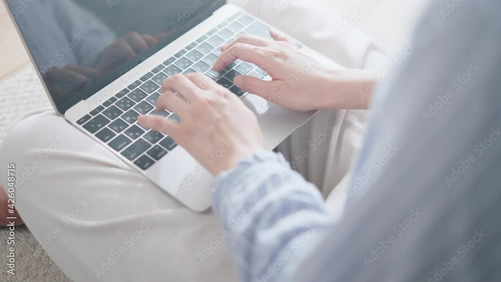 カーペットに座りながらノートパソコンでタイピングをする女性 カーペットに座りながらノートパソコンでタイピングをする女性