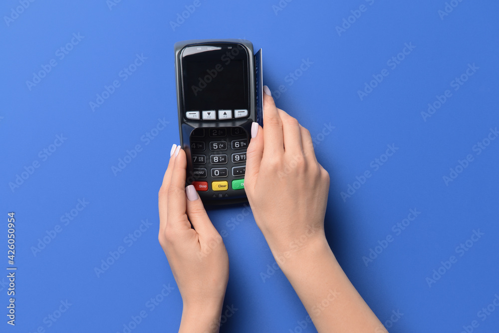 Female hands with credit card and payment terminal on color background Female hands with credit card and payment terminal on color background