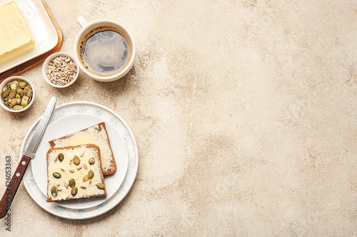 Plate with slices of fresh bread, butter and seeds on light background