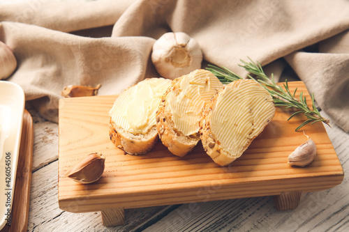 Bild auf Leinwand Slices of fresh bread with butter, rosemary and garlic on light wooden backgroun