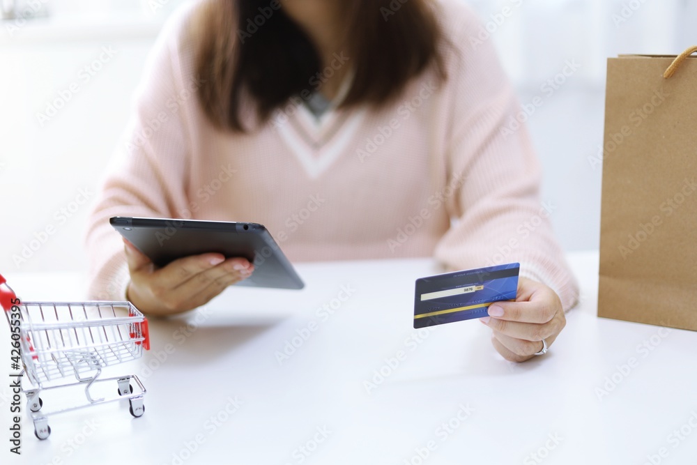 Woman spending money and Small shopping cart with internet banking on Laptop for Internet online e-commerce shopping working from home Woman spending money and Small shopping cart with internet banking on Laptop for Internet online e-commerce shopping working from home
