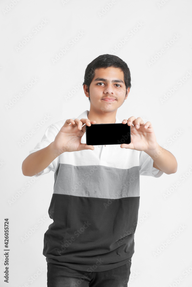 Young indian college student showing smartphone screen on white background. Young indian college student showing smartphone screen on white background.