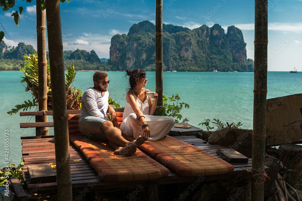 Beautiful couple relaxing on an island off the coast.  Young couple by the sea. A man and a woman travel to Thailand. Couple in love at the lagoon. Honeymoon trip. Relax on the island. Wedding travel
