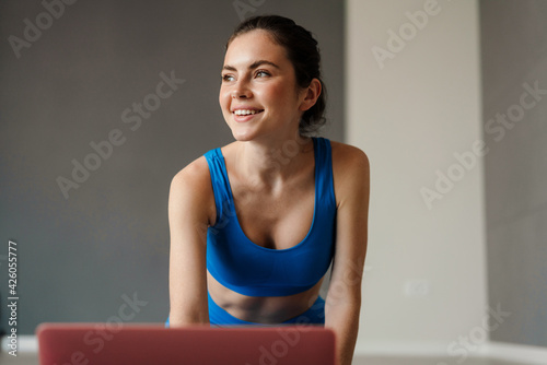 White smiling woman using laptop during yoga practice at home