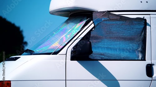 Camper van with internal thermal screen blind at window pane camping on nature in summer. Traveling by motor home. Caravan vacation.