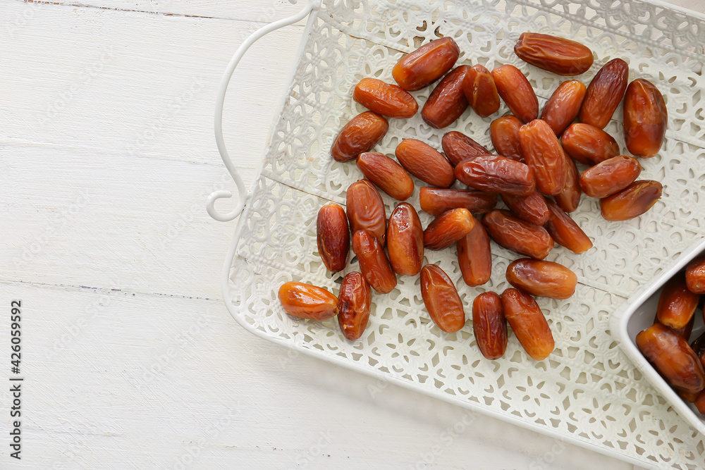Tray with sweet dried dates on light wooden background Tray with sweet dried dates on light wooden background